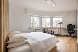 a white bedroom with a bed and a desk and window at 1 bedroom flat 55m2 in the city in Luxembourg