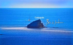 a small island in the middle of the ocean with a boat at Hotel Rec de Palau in Cadaqués