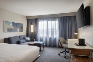 a hotel room with a bed and a living room at Courtyard by Marriott Springfield Airport in Springfield