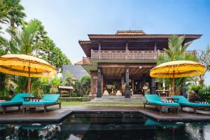 a resort with a pool and chairs and umbrellas at The Joglo at Umah Sunset in Ubud