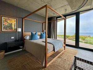 a bedroom with a canopy bed with a view of the ocean at Silver Bay Villa in Stompneusbaai