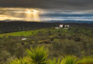vista su una casa su una collina con un arcobaleno di Cortijo señora de las Angustias 2 ad Alanís
