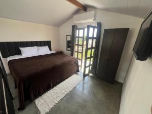 a bedroom with a bed and a sliding door at Chalés Jacumã Paradise in Jacumã