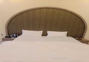 a bedroom with a large bed with a wooden headboard at Hotel R.Raghavam in Ayodhya
