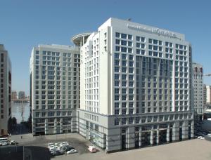 a tall white building with cars in a parking lot at Anwar Al Madinah Mövenpick in Medina