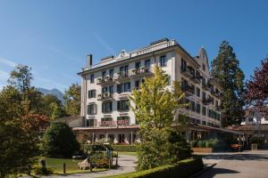 a large white building with trees in front of it at 5th Floor Basic Rooms - shared bathrooms in Interlaken