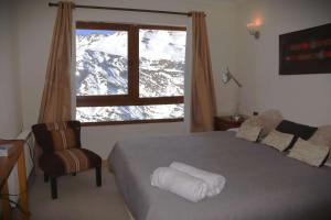 Un dormitorio con una cama y una ventana con montañas cubiertas de nieve en HOM I Vc1702, en Farellones