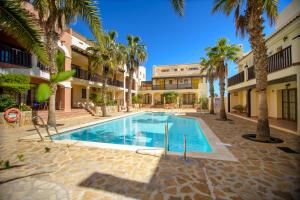 a swimming pool in a courtyard with palm trees at Mediterranea 10 tus momentos junto al mar Villaricos in Cuevas del Almanzora