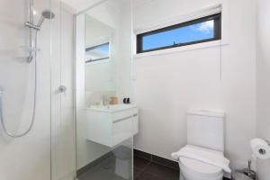 a white bathroom with a toilet and a window at Domi Rentals - The Mill Residence in Clayton North +5 photos