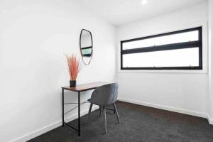 a room with a table and a mirror and a chair at Domi Rentals - The Hampton Homes in Moorabbin