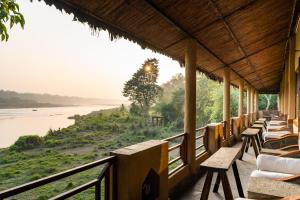a row of benches on a porch looking out over a river at Jungle Villa Resort - Near Chitwan National Park in Chitwan