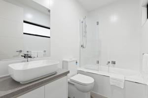 a white bathroom with a sink and a toilet at Domi Rentals - The Hampton Homes in Moorabbin +12 photos