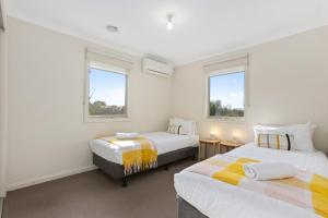 2 letti in una camera con 2 finestre di Domi Rentals The Blackburn Residence a Notting Hill