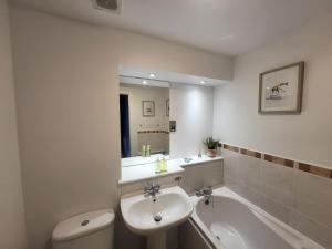 a bathroom with a sink and a toilet and a tub at River Ayr View-Coorie Doon Stays in Ayr +8 photos