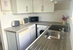 a small kitchen with a sink and a dishwasher at Comfy Staycation! 2BR City Centre Westcliff Beach & High St by Everhome Ltd in Southend-on-Sea