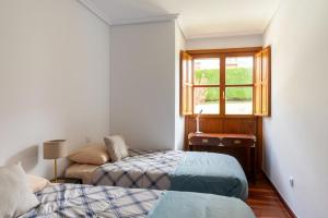 a bedroom with two beds and a window at Piso en Pedreña - 32001 in Pedreña