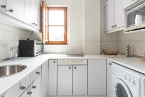 a white kitchen with a sink and a microwave at Piso en Pedreña - 32001 in Pedreña +3 photos