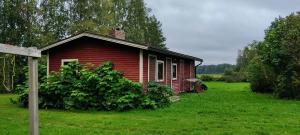 a small red house in a grassy field at Spacious Apartment for 8 with Sauna in Sievi