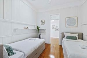 two beds in a room with white walls and wooden floors at Family Friendly, Pool, 9km to City by Custom Bnb Hosting in Brisbane +14 photos