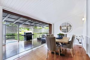 a living room with a table and chairs and a balcony at Family Friendly, Pool, 9km to City by Custom Bnb Hosting in Brisbane