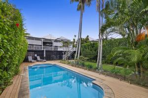 a swimming pool in front of a house with palm trees at Family Friendly, Pool, 9km to City by Custom Bnb Hosting in Brisbane