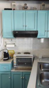 eine Küche mit blauen Schränken und einem Herd mit Backofen in der Unterkunft Chrysa's cottage house in Karystos