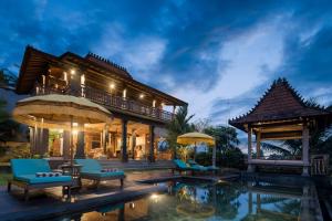 a villa with a swimming pool at night at The Joglo at Umah Sunset in Ubud