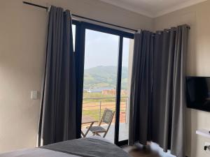 a bedroom with a sliding glass door with a view at The Gorge View at Highland Gate in Dullstroom