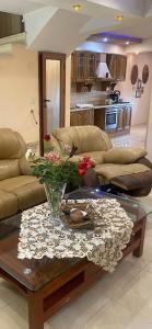 a living room with a couch and a table with flowers at Мезонет “Djanina” in Sandanski