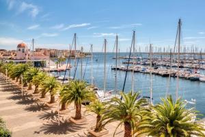 a marina with palm trees and boats in the water at Lo Nidou Gruissan in Gruissan