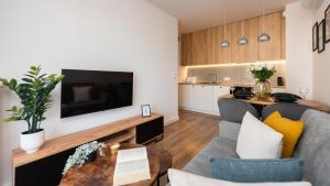 Una sala de estar con un sofá y un televisor. en Flatbook Apartamenty - Trimare Sztutowo z bilardem i parkingiem, en Sztutowo