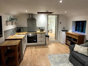 a kitchen with a stove and a couch in a room at The Bakehouse in Castlemorton