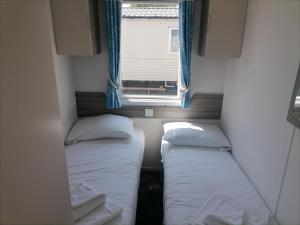 two beds in a small room with a window at Seaside retreat - 3 bedrooms with decking sleeps 8 in Kent