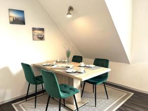 a dining room with a table and green chairs at Ferienwohnung Leuchtfeuer Dagebüll in Dagebüll