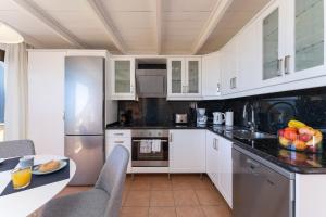 una cocina con armarios blancos y una mesa con un bol de fruta en Beach House Monte Rojo, en San Agustín