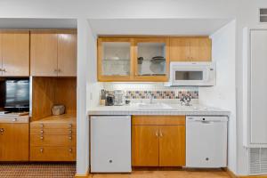 a kitchen with white appliances and wooden cabinets at Palisades Tahoe Lodge Rentals Studio #115 in Olympic Valley