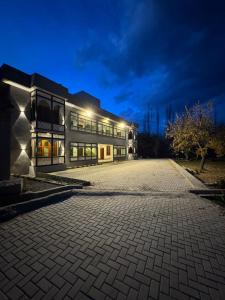 a building with a cobblestone parking lot at night at Summit Hotel Skardu in Skardu