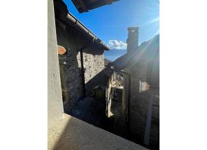 una vista desde el callejón de un edificio con el sol brillando en Casa delle Antiche Pietre, en Cannero Riviera