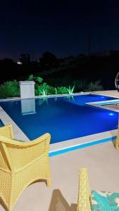 a patio with two chairs and a pool at night at Margarida 04 in Monte das Gameleiras +8 photos
