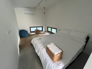 a bedroom with a white bed with a basket on it at Anping Lounge in Tainan