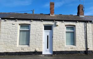 a stone house with a white door and windows at Sea Glass Cottage in Sunderland