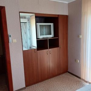 a room with a television and a cabinet with a mirror at Enjoy Guest House in Golden Sands