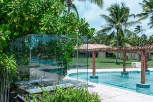 a glass house with a pool and palm trees at Reserva Jacumã Boutique Hotel in Trancoso