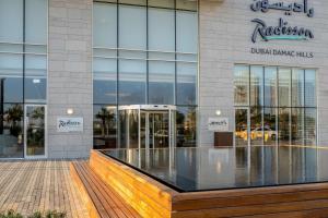 a building with a sign on the side of it at Radisson Dubai Damac Hills in Dubai