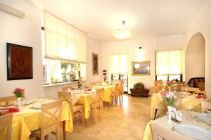 a restaurant with tables and chairs with yellow table cloth at Hotel Gambone in Finale Ligure