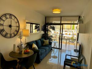 a living room with a blue couch and a clock at Blue Beach in Playa del Ingles