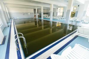 an empty swimming pool with chairs in a building at Hotel Dobsi in Bazna