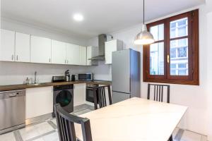 a kitchen with a table and a refrigerator at Charming 4 Double Bed Steps from the Old Town in Bilbao
