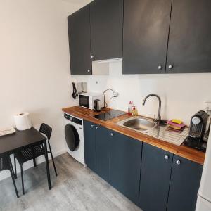 a kitchen with blue cabinets and a sink and a table at Jardin Briand in Champigny-sur-Marne