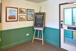 a chalkboard sign on a tripod next to a door at Craigside Manor in Llandudno